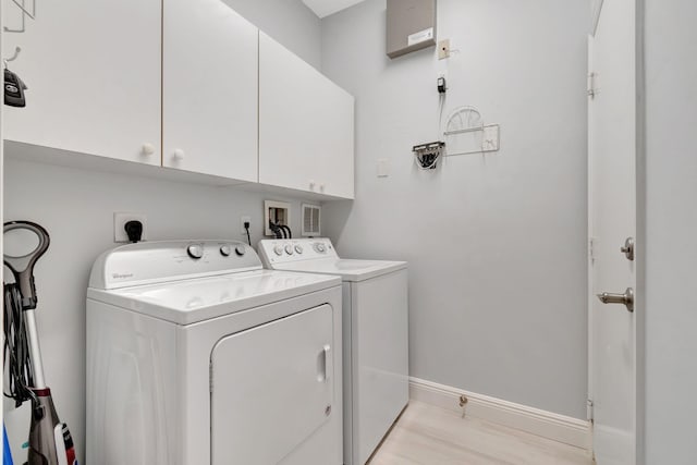 clothes washing area featuring washing machine and dryer, cabinets, and light hardwood / wood-style flooring