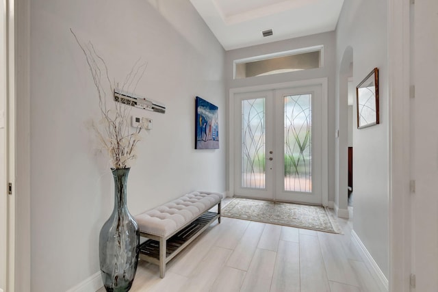 foyer featuring a tray ceiling, french doors, and light hardwood / wood-style floors