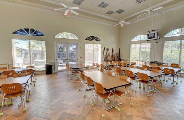 dining area with a high ceiling, ornamental molding, ceiling fan, and light parquet flooring