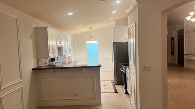 kitchen featuring light tile patterned flooring, lofted ceiling, kitchen peninsula, white cabinetry, and stainless steel appliances