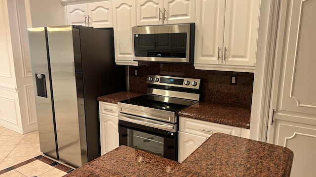 kitchen featuring tasteful backsplash, dark stone countertops, stainless steel appliances, and white cabinets