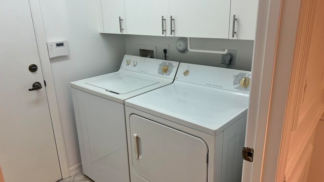 clothes washing area featuring cabinets, washing machine and clothes dryer, and light tile patterned flooring