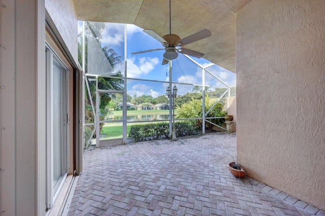 unfurnished sunroom with lofted ceiling, a water view, and ceiling fan