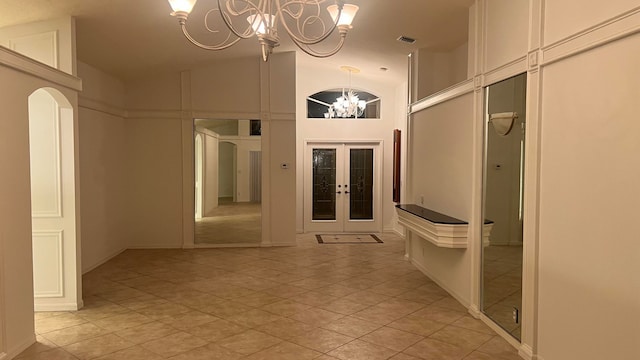 hallway with an inviting chandelier, light tile patterned flooring, high vaulted ceiling, and french doors