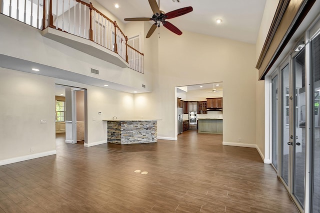 unfurnished living room with dark hardwood / wood-style floors, ceiling fan, and a towering ceiling