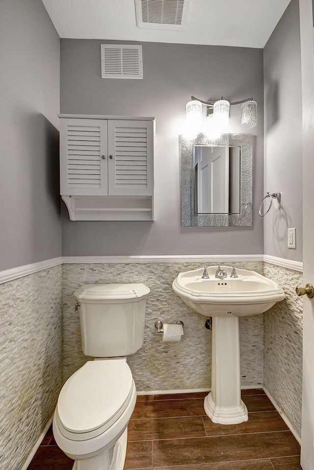 bathroom with hardwood / wood-style floors, toilet, and tile walls