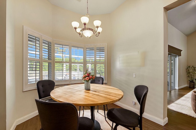 dining space featuring dark wood-type flooring, a high ceiling, and an inviting chandelier