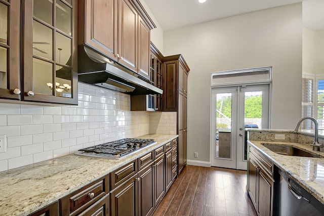 kitchen featuring light stone countertops, backsplash, stainless steel appliances, dark wood-type flooring, and sink