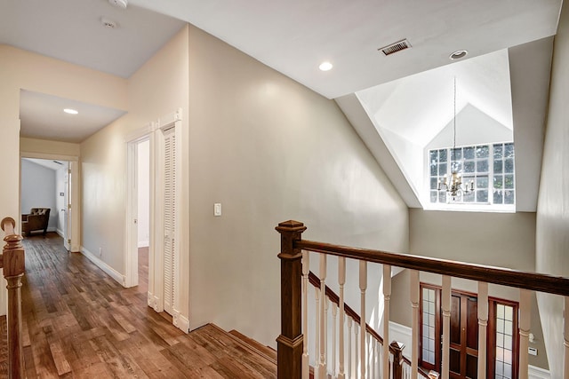 corridor with hardwood / wood-style flooring and a chandelier