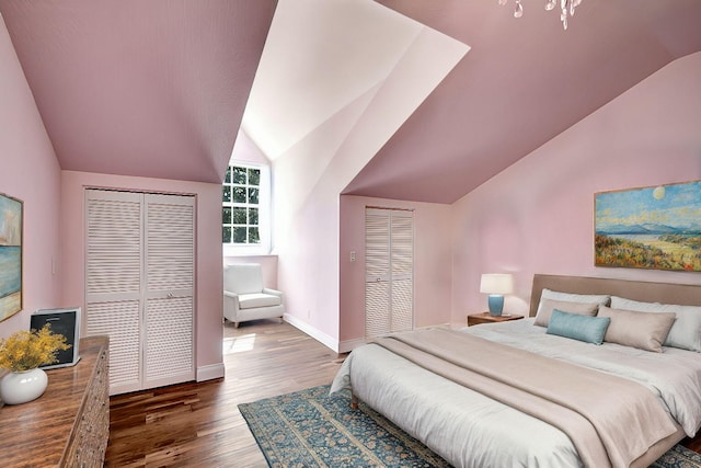 bedroom with multiple closets, dark hardwood / wood-style flooring, and lofted ceiling