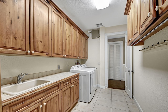 washroom with washer and clothes dryer, cabinets, sink, light tile patterned floors, and a textured ceiling