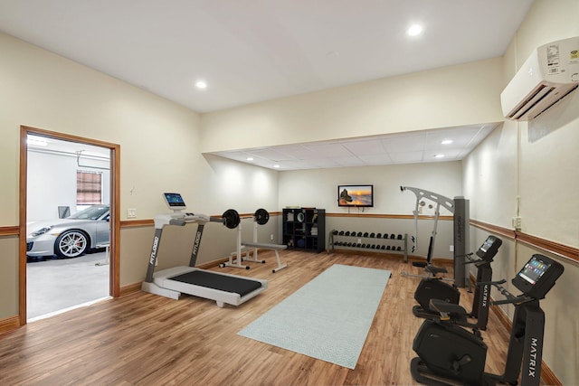 exercise area with a wall mounted AC and hardwood / wood-style floors