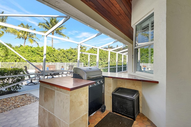 view of patio with exterior bar, glass enclosure, and area for grilling