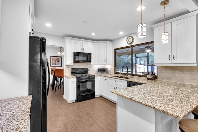 kitchen with sink, kitchen peninsula, tasteful backsplash, and black appliances