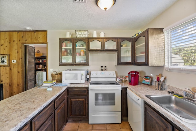 kitchen with light tile patterned floors, white appliances, sink, and a textured ceiling