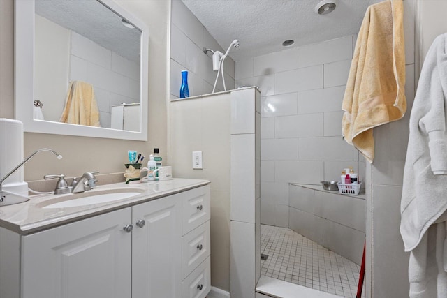 bathroom with vanity, a tile shower, and a textured ceiling