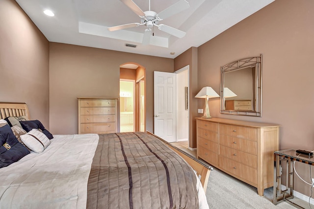 carpeted bedroom with ensuite bath and ceiling fan