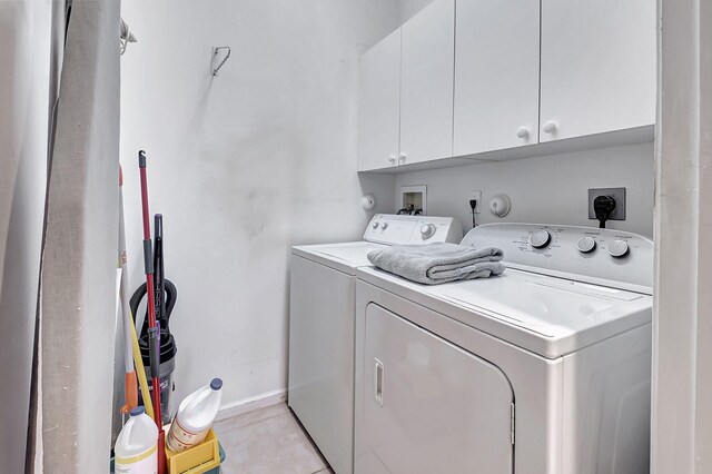 washroom with cabinets, washing machine and dryer, and light tile patterned floors