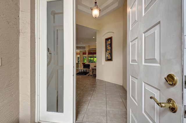 interior space featuring light tile patterned flooring and a raised ceiling