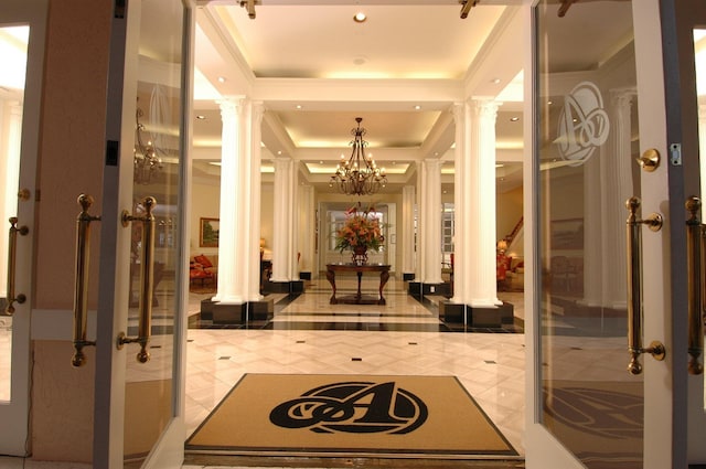 interior space with ornate columns, a raised ceiling, and a chandelier