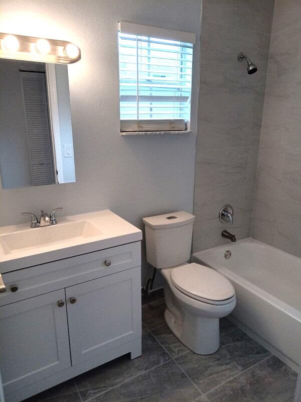 full bathroom with vanity, tile patterned flooring, tiled shower / bath, and toilet