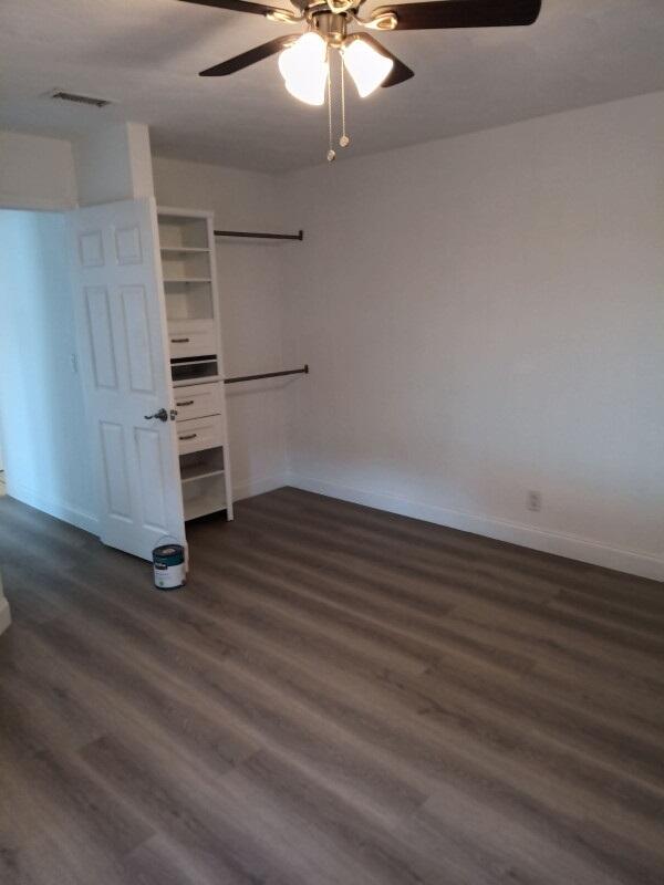 unfurnished bedroom featuring ceiling fan and dark hardwood / wood-style flooring