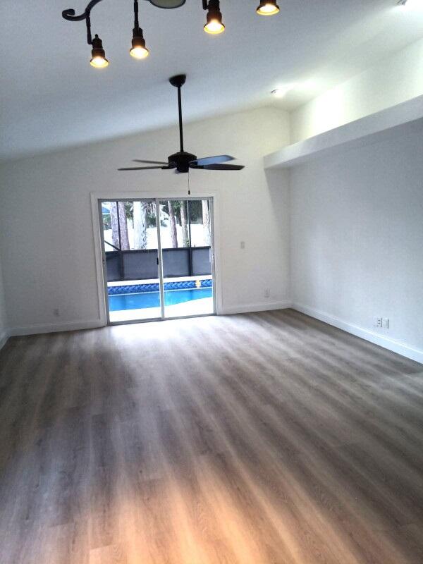 unfurnished room with lofted ceiling, hardwood / wood-style flooring, and ceiling fan