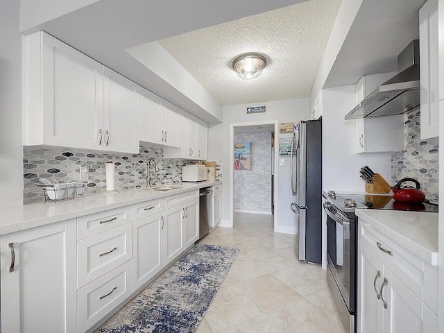 kitchen with tasteful backsplash, sink, white cabinetry, stainless steel appliances, and wall chimney exhaust hood