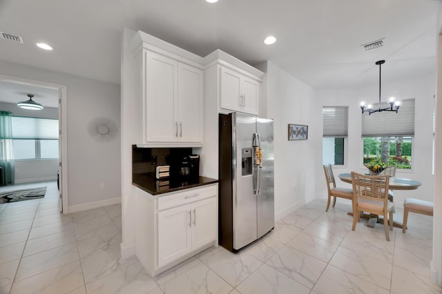 kitchen featuring a wealth of natural light, stainless steel fridge with ice dispenser, hanging light fixtures, and white cabinets