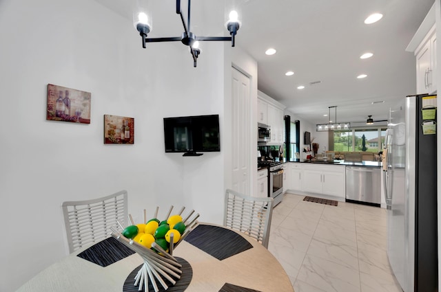 kitchen with appliances with stainless steel finishes, kitchen peninsula, white cabinetry, and hanging light fixtures