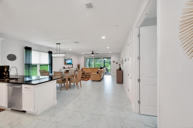 kitchen featuring ceiling fan with notable chandelier, decorative light fixtures, white cabinetry, sink, and stainless steel dishwasher