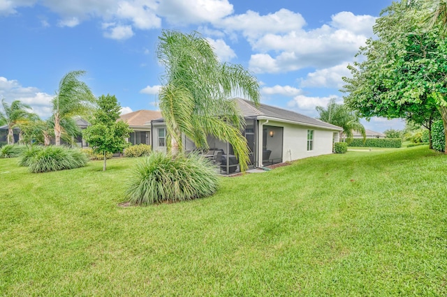 rear view of house featuring a yard and a sunroom