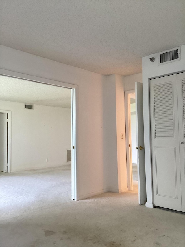 carpeted empty room featuring a textured ceiling