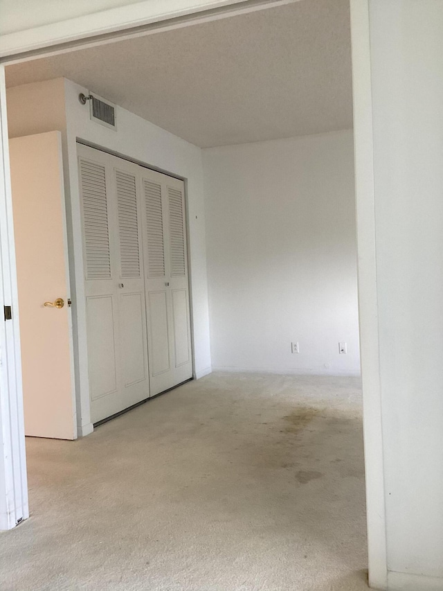 unfurnished bedroom with light carpet and a closet