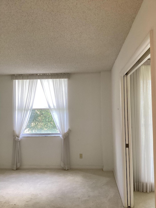 unfurnished room featuring a textured ceiling and light colored carpet