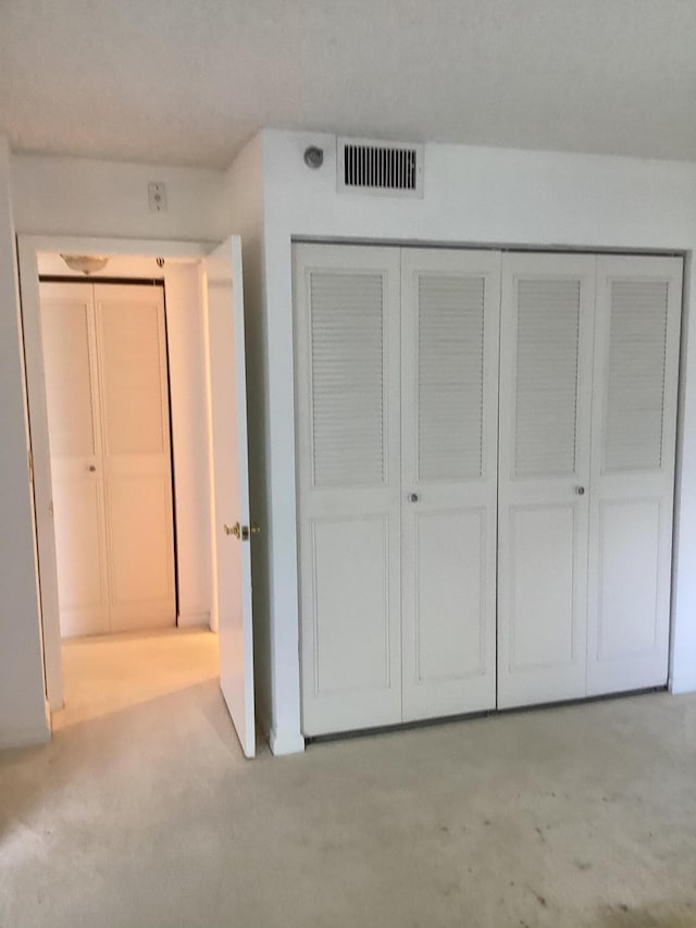 unfurnished bedroom featuring a closet and light colored carpet