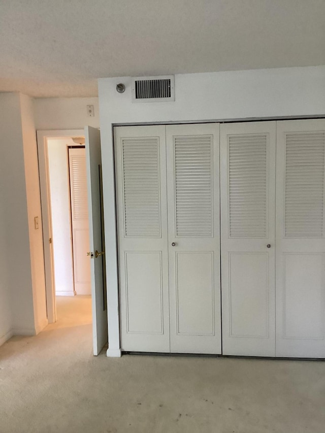 unfurnished bedroom with light carpet and a closet