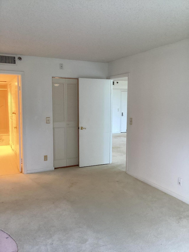 unfurnished bedroom with light carpet and a textured ceiling