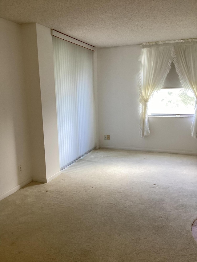 carpeted empty room featuring a textured ceiling