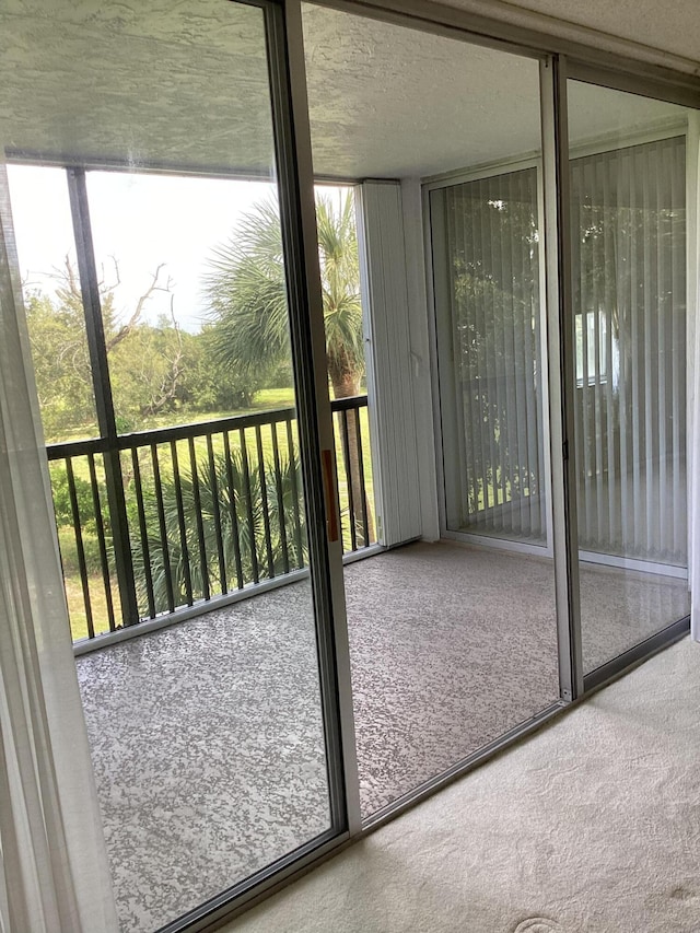 doorway to outside featuring carpet floors and a textured ceiling