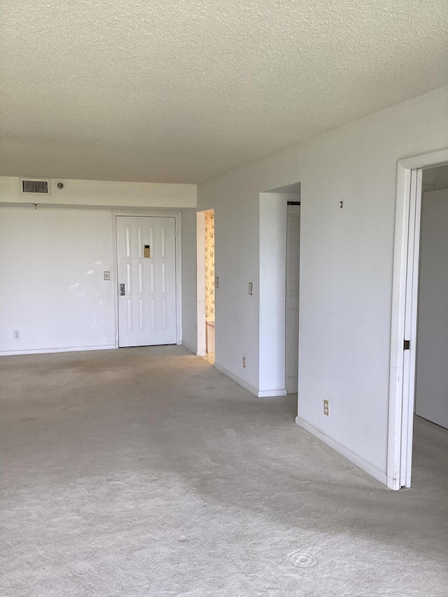 spare room with a textured ceiling and light colored carpet