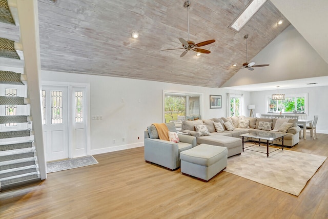 living room featuring ceiling fan with notable chandelier, a wealth of natural light, a skylight, and high vaulted ceiling