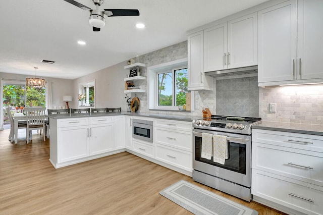 kitchen with hanging light fixtures, kitchen peninsula, white cabinetry, stainless steel appliances, and ceiling fan with notable chandelier