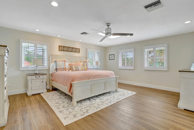 bedroom featuring light hardwood / wood-style flooring, ceiling fan, and multiple windows