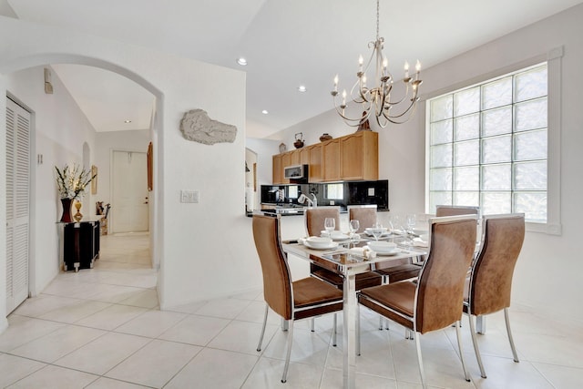 dining area featuring lofted ceiling, light tile patterned flooring, and a notable chandelier