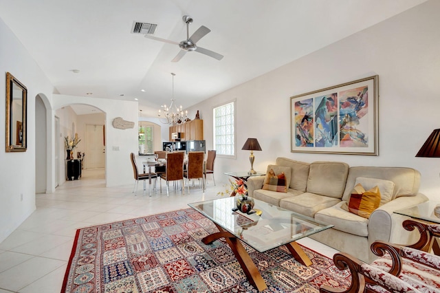 living room featuring lofted ceiling, light tile patterned floors, and ceiling fan with notable chandelier