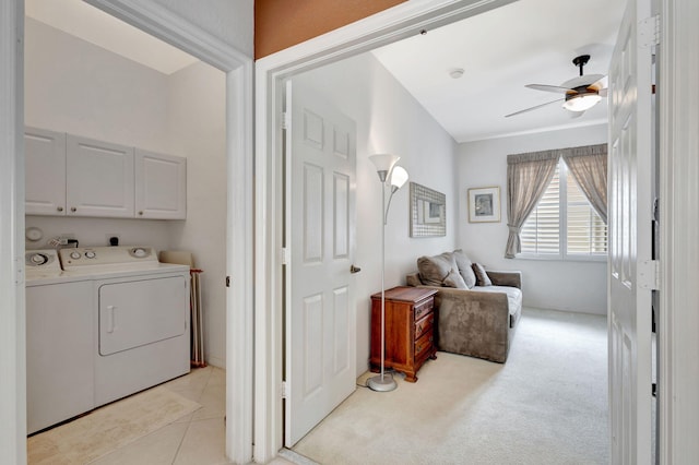 clothes washing area with ceiling fan, washing machine and dryer, light colored carpet, and cabinets