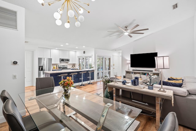 dining area with visible vents, vaulted ceiling, and light wood finished floors