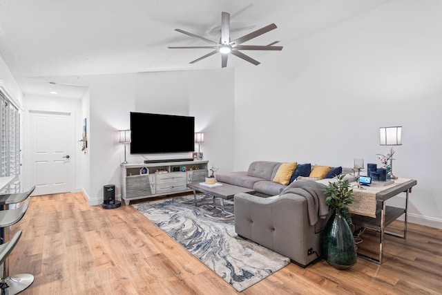 living room with a ceiling fan, baseboards, and wood finished floors