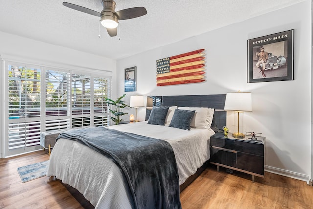 bedroom with a textured ceiling, wood finished floors, a ceiling fan, and baseboards